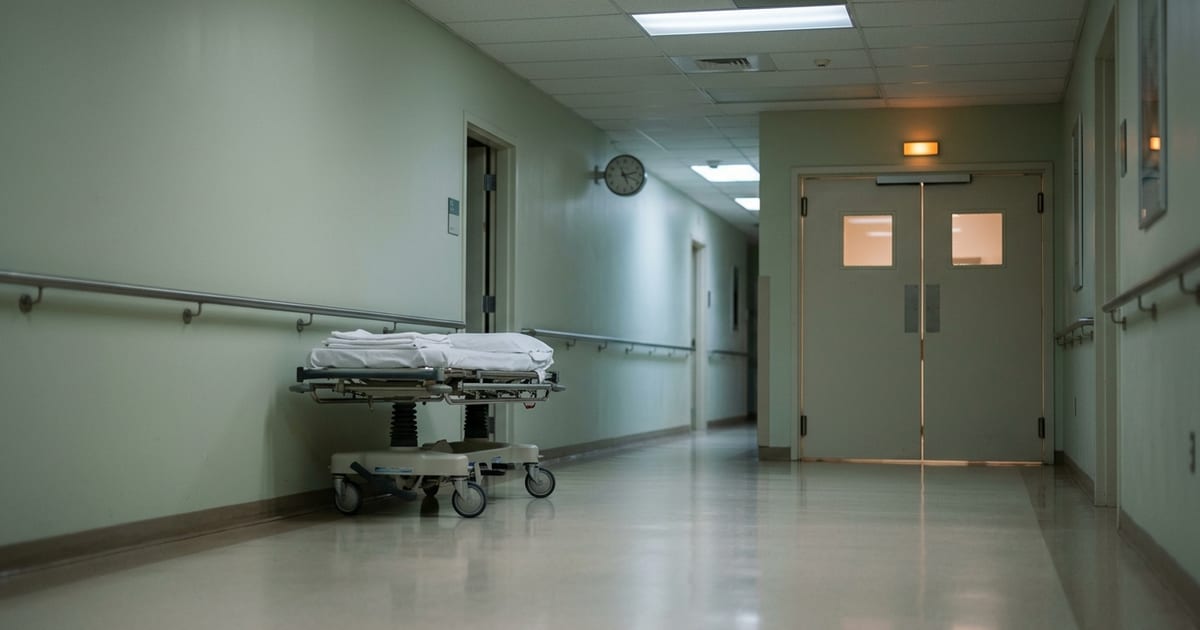 Corredor de hospital à noite com porta de centro cirúrgico ao fundo