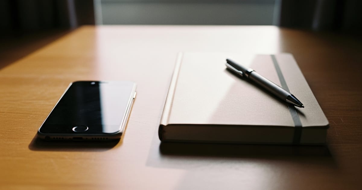 Tela de celular com aplicativo de pagamentos sobre uma mesa de trabalho