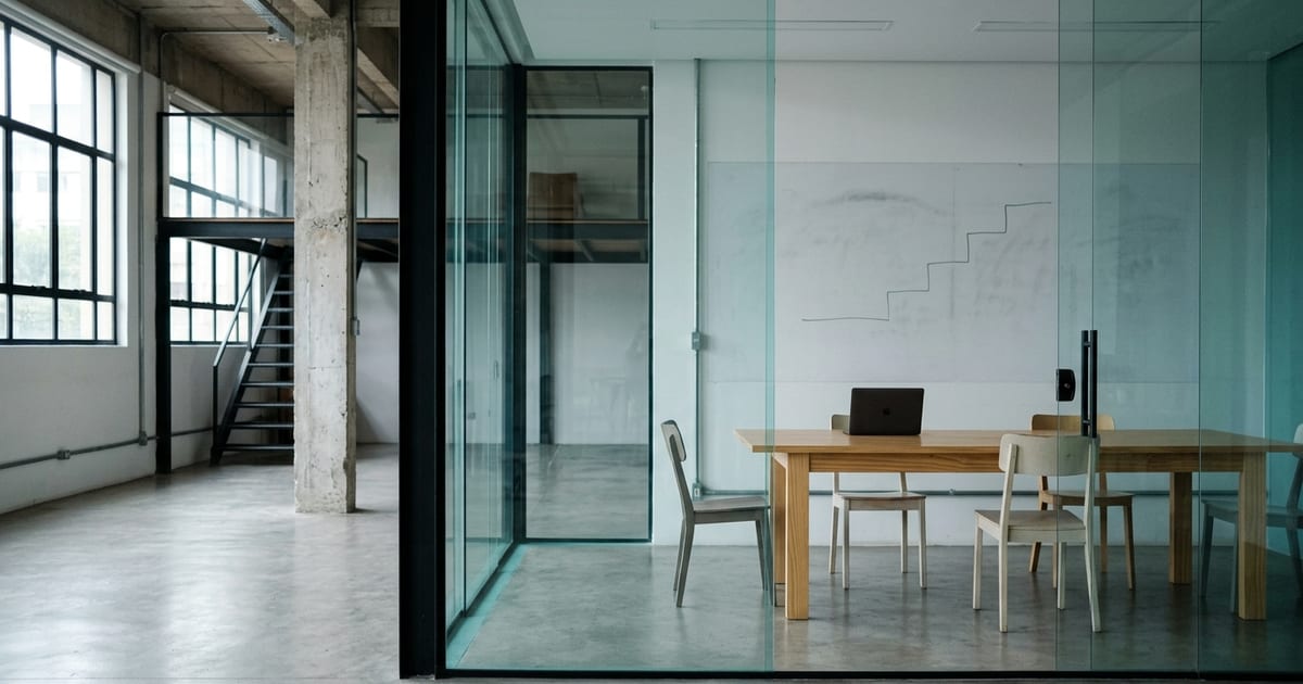 Sala de reunião de startup com quadro branco apagado, cadeiras e notebooks sobre a mesa